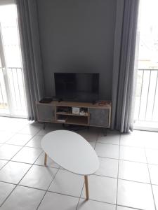 Il comprend un salon doté d'une télévision et d'une chaise blanche. dans l'établissement Appartement village Le Liberty 3 Argelès Sur Mer 2km plage, à Argelès-sur-Mer
