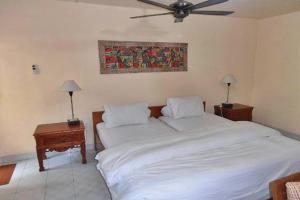 een slaapkamer met 2 bedden en een plafondventilator bij Nakula Familiar Inn in Denpasar