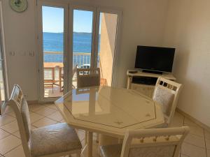een eetkamer met een tafel en een televisie en een balkon bij Le Latania in Sainte-Maxime