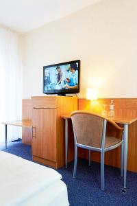 a hotel room with a television and a table and chair at Haus Niemann in Münster