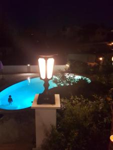 una lámpara frente a una piscina por la noche en Villa Clematis, en Trogir