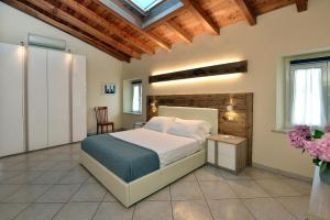 Antiche Rive Holidays Apartments في سالو: غرفة نوم بسرير كبير وسقف خشبي