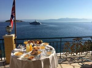 a table with food and a cruise ship in the water at Margina Residence Hotel in Gaios