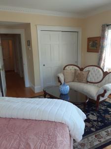 a bedroom with a bed and a couch and a table at The Victoria Inn Bed & Breakfast in Hampton