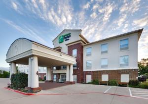 ein Hotel mit einem Schild auf der Vorderseite eines Gebäudes in der Unterkunft Holiday Inn Express Hotel & Suites Cleburne, an IHG Hotel in Cleburne