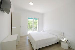 a white bedroom with a bed and a tv at Apartaments Àlex in Cambrils