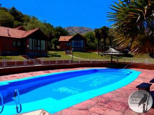 a swimming pool in front of a house at Cabañas El Refugio de los Pajaros in Merlo
