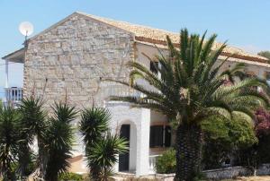 a stone house with palm trees in front of it at Elli Beach Apartments and Studios in Almiros Beach