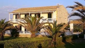 a large house with palm trees in front of it at Elli Beach Apartments and Studios in Almiros Beach