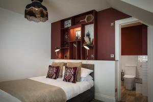 1 dormitorio con paredes rojas y 1 cama con almohadas en The Bath Hotel, en Lynmouth