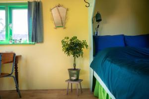 Un dormitorio con una cama azul y una planta en un taburete en Shanti B&B en Deventer