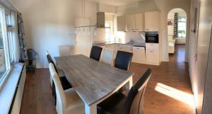 cocina y comedor con mesa de madera y sillas en Vakantiehuis de Turfvaart, en Wachtum