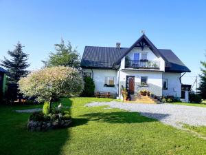 a white house with a tree in the yard at Apartament w Oklinach in Wiżajny