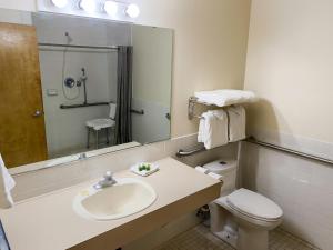 ein Badezimmer mit einem Waschbecken, einem WC und einem Spiegel in der Unterkunft Sisters Inn & Suites in Sisters