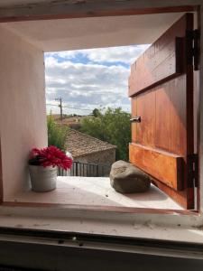 uma janela aberta com um vaso de flores no parapeito da janela em Casa da Azinheira em Farelos de Baixo