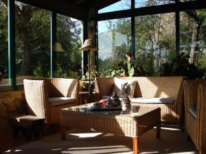 a screened in porch with wicker chairs and a table at Quinta Verde Sintra - Casa de Campo in Sintra