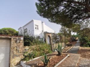una casa blanca con una valla y algunas plantas en Entre pinos y playa, en Matalascañas