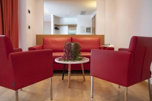 a living room with a red couch and a table at B&B HOTEL Remilia in Reggio Emilia