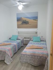 una habitación con 3 camas y una foto de un desierto en Apartamento la piedra viva 3 arinaga, en Arinaga