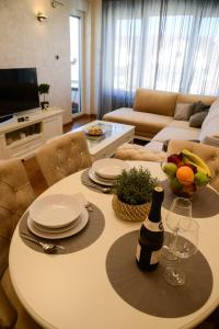 uma sala de estar com uma mesa com pratos e copos de vinho em Tesla 70 Apartment with secure parking In the garage em Novi Sad
