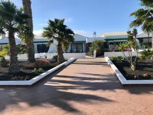 a courtyard with palm trees and a building at Casa Maiakai in Playa Blanca