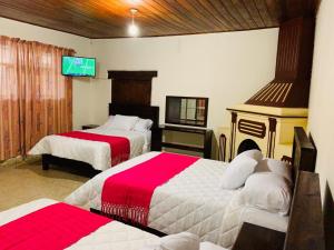 a hotel room with two beds and a tv at HOTEL CASA D'LINA CENTRO in San Cristóbal de Las Casas