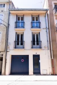 a white building with a black gate and two balconies at Maison La Majorelle - 90m2 - Garage et Terrasse in Pamiers
