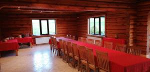 a dining room with red tables and chairs and windows at Lielkaibeni in Vecpiebalga
