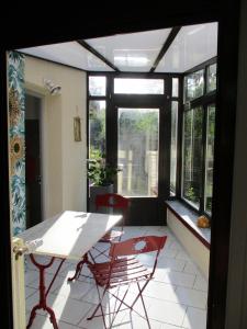 een kamer met een tafel, stoelen en ramen bij GÏTE LE CONFLUENT in Vireux-Molhain