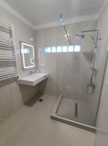a white bathroom with a shower and a sink at Regal Marine in Eforie Nord