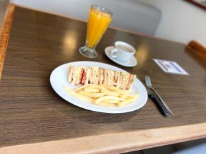 a plate with a sandwich and french fries and a glass of orange juice at Hotel Roble in Mexico City