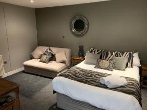 1 dormitorio con 2 camas y sofá en The Peacock, en Bakewell