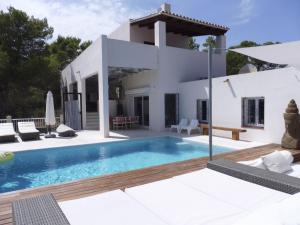 a villa with a swimming pool in front of a house at Belvilla by OYO Casa Loma in Cala Tarida