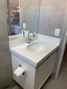 a bathroom with a white sink and a mirror at Fb HOME Guaruja- Apartamento proximo as praias da Enseada e Pitangueiras - WI FI in Guarujá