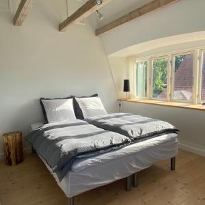łóżko w białym pokoju z oknem w obiekcie Birgittes B&B i Jelling w mieście Jelling