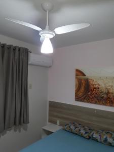a ceiling fan in a room with a bed and a painting at Aldeia do Lago C405-churrasqueira, bebidas liberadas nas piscinas, internet no ap, rampa de acesso ao lago, recarga carro elétrico, pesqueiro in Caldas Novas