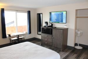 a bedroom with a bed, desk and television at Inn at the Sea in Long Beach
