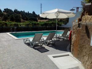 un grupo de sillas y una sombrilla junto a la piscina en Quinta Ribeiro Tanquinhos, en Tancos