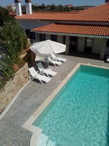 a swimming pool with two lawn chairs and an umbrella at Quinta Ribeiro Tanquinhos in Tancos