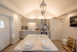 a kitchen with a table with plates and glasses on it at Old Spot Cottage in Tickton