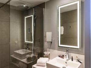 a bathroom with a sink and a mirror and a shower at Novotel Saint-Étienne Centre Gare Châteaucreux in Saint-Étienne