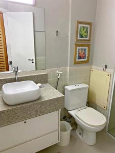 a bathroom with a toilet and a sink and a mirror at Boulevard Riviera Flat in Riviera de São Lourenço