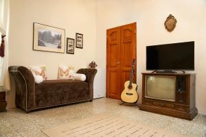 a living room with a couch and a tv and a guitar at Hotel Vintage "Rialto" in Quetzaltenango