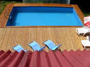 three chairs and a swimming pool on a deck at Vila Roseta in Cărbunari