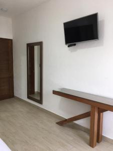 a flat screen tv on a white wall with a bench at Hotel Concierge Flor y Canto in Tepoztlán