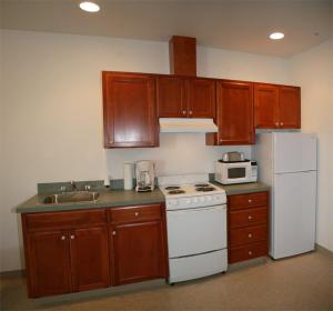 La cuisine est équipée de placards en bois, d'une cuisinière blanche et d'un réfrigérateur. dans l'établissement Ponderosa Motel, à Goldendale