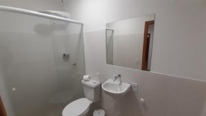 a bathroom with a toilet and a sink and a mirror at Suite climatizada, ao lado da praca principal in Domingos Martins