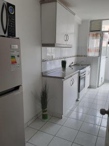 a kitchen with white appliances and a white tile floor at Departamento Amueblado in Antofagasta