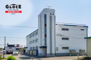 a white building with a clock on the side of it at GLOCE 美幌 ゲストルーム l BIHORO Guest room in Bihoro