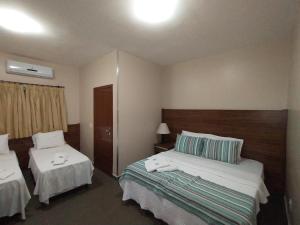 um quarto de hotel com duas camas e duas mesas em Hotel Albatroz em Uberaba